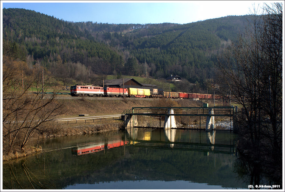 Am 23. Mrz 2011 ziehen eine unbekannte 1142 und eine unbekannte 1144 bei Schlglmhl einen Gterzug ber den Semmering und spiegeln sich in der aufgestauten Schwarza.
