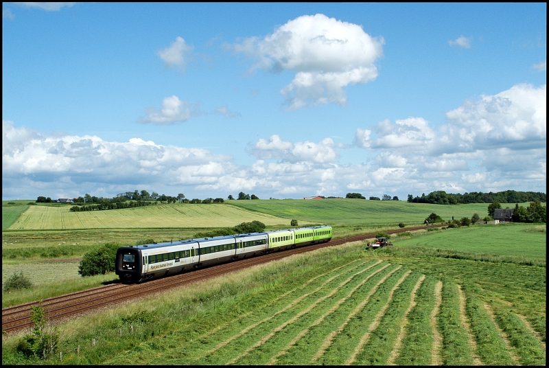 Am 25.06.2010 ging's an die Strecke zwischen Arhus und Aalborg in die Nhe von Handest. Viel interessanter Verkehr war nicht zu erwarten, schlielich fhrt nrdlich von Arhus in der ganzen Woche nur 1 Gterzugpaar und dass auch noch in Tagesrandlage. Den Fotopunkt hatte ich mir schon vor dem Urlaub ber GE rausgesucht. Und siehe da, vor Ort angekommen hatte Petrus ein Einsehen und zog einen wunderbar kitschigen Postkartenhimmel aus dem Hut. Auch der Bauer htte sich fr seine Arbeit mit Traktor und Schwadmher kaum einen besseren Zeitpunkt aussuchen knnen. Also warten und hoffen ... Nachdem schon 2 Triebwagen aus der Gegenrichtung den Fotopunkt passiert hatten und der Bauer mit seiner Arbeit fast fertig war, sah ich meine Felle schon wegschwimmen. Um so grer war dann die Freude, als mit ICL 43 von Kbenhavn H nach Aalborg st ein Zug aus der richtigen Richtung kam, der mit MF 5088 und MF 5075 eine nette farbliche Kombination zu bieten hatte.