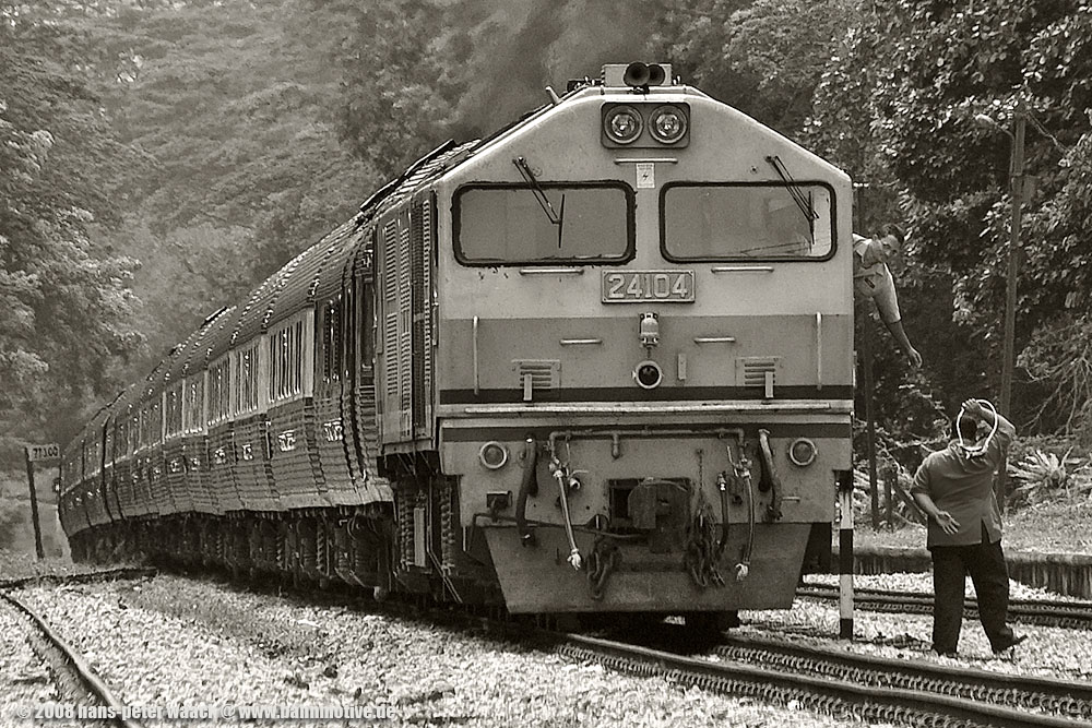 Am 27.12.08 kommt der Eastern&Oriental Express mit 24 104 der KTM, der von Singapur nach Bangkok unterwegs ist, durch den Bahnhof Singapur Bukit Timah. Der Lokfhrer bernimmt den  Token , eine Art Staffelstab, der ihm gestattet, in den nchsten Abschnitt einzufahren. Einfache Sicherungstechnik, aber funktioniert, wenigstens bei einfachen Verhltnissen.