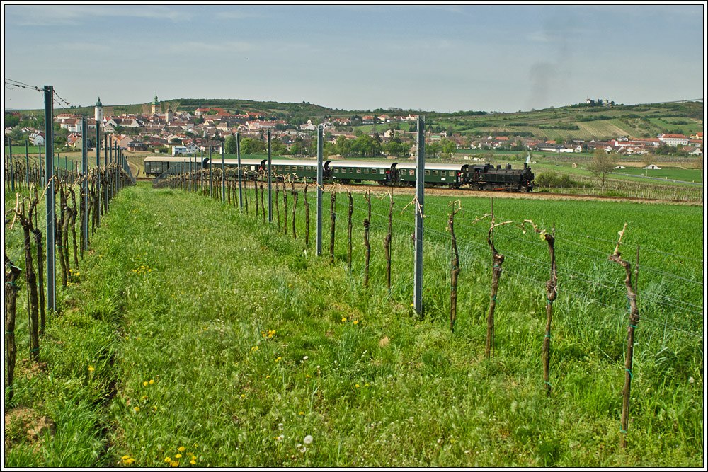 Am 29.4.2012 wurde die heurige  Reblaus Express  Saison mit einem Dampfsonderzug, gefhrt von der 93.1420 des Vereines  Neue Landesbahn  erffnet. Leider stand die Fahrt unter keinem guten Stern. Aufgrund div. Bschungs- und Flurbrnde musste die zweite Fahrt der Dampflok abgesagt werden, sie verblieb auf der Rckfahrt im Bahnhof Weitersfeld. Die Fahrten wurden mit Diesellok BR 2070 fortgesetzt....
Hier der Zug mit 93.1420 vor der bekannten Stadtkulisse in Retz. Da die bekanntere Stelle (weiter rechts) schon von Dornenbschen zugewachsen ist, entschied ich mich fr diese Ansicht aus dem Weingarten (um nicht im Feld zu stehen). Dafr kann man hier auch die Retzer Windmhle aufs Bild kriegen.....