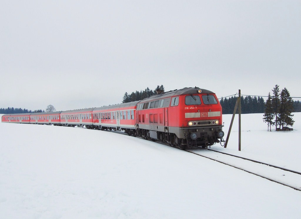 Am 30.12.10 trat ich endlich mal eine Reise an die Knig-Ludwig-Bahn an, um dort im ersten Wagen hinter der 218 eine Mitfahrt zu machen. Natrlich wollte ich auch noch ein Bild machen, um die Erinnerung an diese Fahrt fest zu bewahren. Aus diesem Grund wurde auf der Rckfahrt ein Zwischenstopp in Weizern-Hopferau gemacht. Nach einer kleinen Wanderung war auch ein geeigneter Fotostandpunkt gefunden. Das Einzige, was nun also noch fehlte, war die vorhergesagte Sonne, doch jene wollte sich einfach nicht zeigen. Dies strte 218 454-7 vom Betriebshof Kempten wenig, denn die Lok zieht hier bei Weizern ihren RE 57510 mit nur sehr geringer Versptung in Richtung der vor allem bei Touristen beliebten Stadt Fssen. Ein Gru geht an den Lokfhrer sowie den freundlichen Schaffner! 