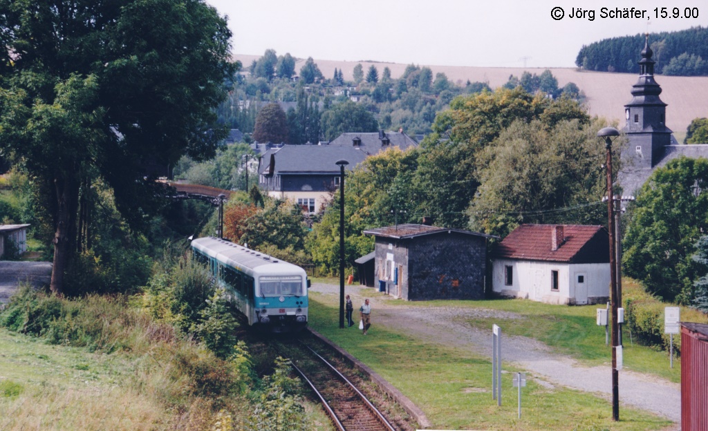 Am Nordrand von Harra liegt der Haltepunkt im Einschnitt zwischen zwei Straenbrcken. Von der Bahnhofstrae Richtung Osten sieht man vorne 628 803 am Bahnsteig und dahinter den Schloberg. (15.9.00)