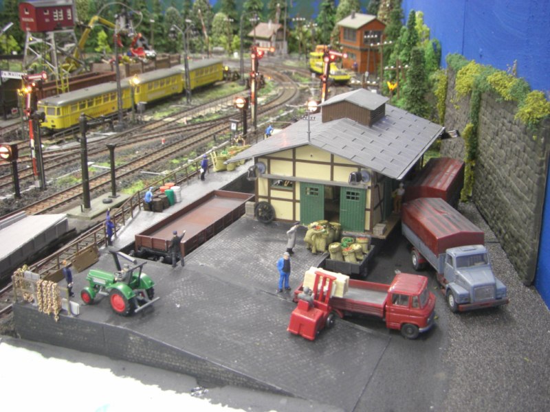 An der Gterhalle sind schon erste LKW's eingetroffen, sowie der Landmaschinenhndler der seinen Traktor verladen mchte.
Der entsprechende Waggon steht schon bereit. Whrend Staplerfahrer Klaus unter Beobachtung des LKW Fahrers Franz eine Kiste entldt.