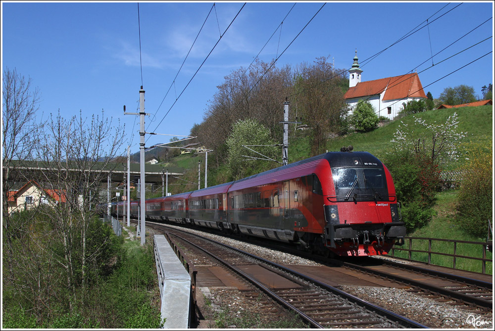 An der St. Nikolaus Kirche vorbei, schiebt 1116 245 den Railjet 557 in Richtung Graz.   
Bruck an der Mur 27.4.2012