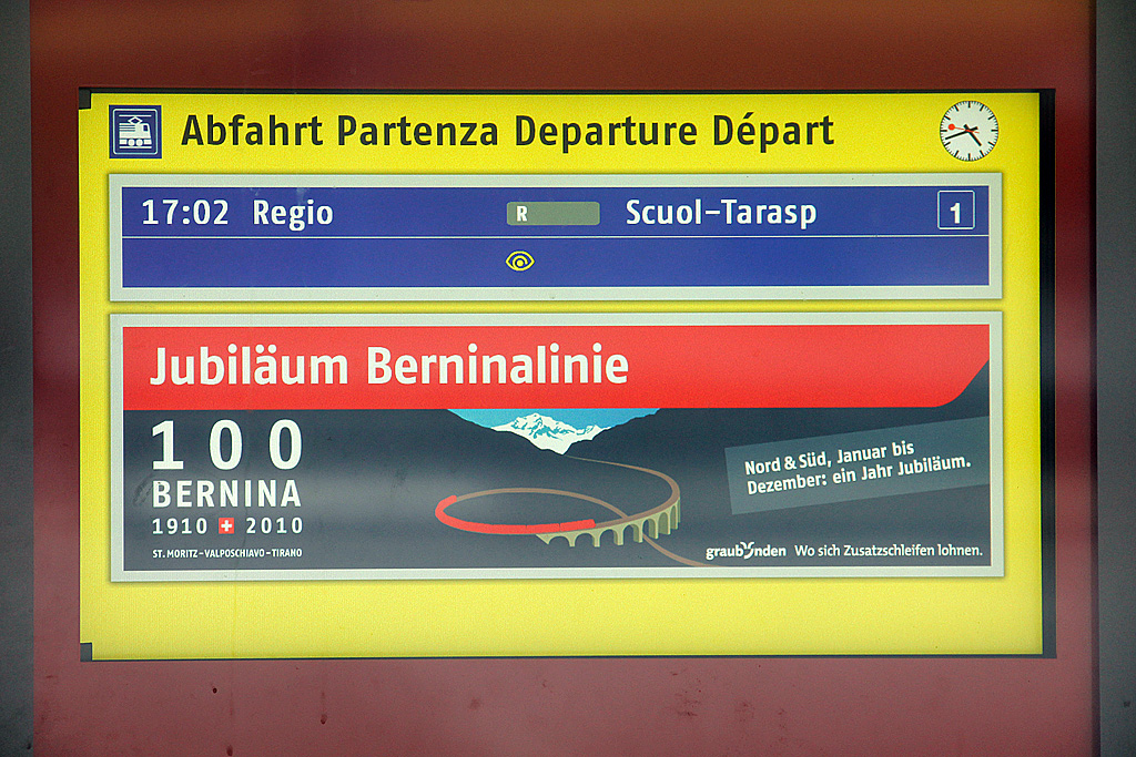 Anzeigetafel zeigt nchste Abfahrt auf Gleis 1 an: Regio nach Scuol-Tarasp. Darunter gibts alternierend RhB-Eigenwerbung. Bahnhof Pontresina, 13. Okt. 2010, 16:49