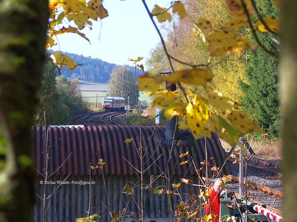 Auch an der kleinen Anrufschranke zwischen Hof und M�nchberg im Wald hab ich versucht, mit Blick durch die Haupt�ste des Baumes den Herbst einzufangen. Wg. Waldarbeiten war am 18.10.2010 die Schranke sogar besetzt. Nachdem ich kurz vor dem Bild vom Baum fiel, weil mein Halteast abbrach, gelang dennoch das Bild (voller Einsatz also inkl. versauter Hose). Der nette DBler guckt hier ersichtlich nach mir. Hinten naht der 628er aus M�nchberg und rechts sieht man die Schranke. Nicht auf dem Bild ist das riesige R�ckfahrzeug was den Feldweg dorthin nicht ganz unbearbeitet liess....