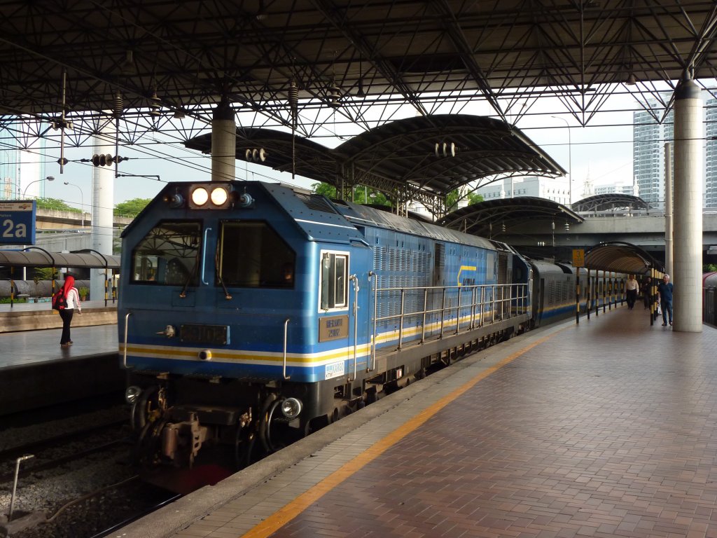 Auf dem Weg von Singapore nach Butterworth passiert der Ekspres Rakyat den alten Bahnhof von Kuala Lumpur am 18.4.2011. Eine Besonderheit vieler Malaysischer Zge sind die Generatorwagen, der hier direkt hinter der Lok eingereiht ist.