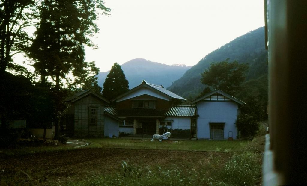 Auf der Fahrt kommt Wagen 3744 auf dem heute aufgehobenen Abschnitt tief ins Bergtal hinein an einem Bergbauernhof vorbei. Kaga Kawai, 30.September 1984. 