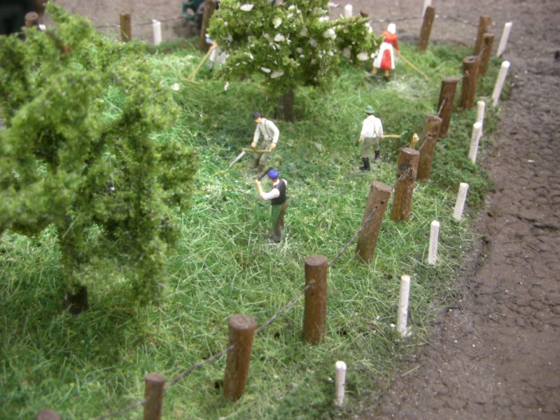 Auf der kleinen Wiese ist die Bauernfamilie bei der Heuernte