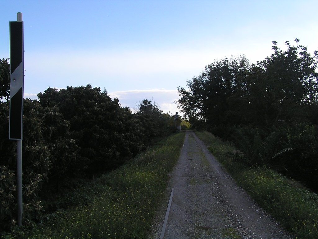 Aufgelassene und hier in Schotterstrae umgewandelte Strecke Alcantara<>Randazzo; 100 m bis Bahnbergang der via Santa Filomena. Im Hintergrunde sieht man noch das  Vorsignal von Alcantara (02.12.2012)