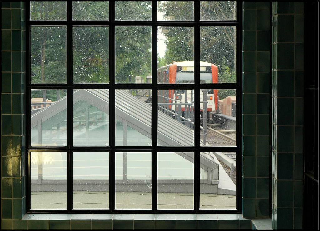 Ausfahrt eines Zuges der Hamburger U-Bahnlinie U3 aus der Station  Sierichstrae , gesehen durch ein Fenster des rekonstruierten Treppenabgangs. 11.8.2013