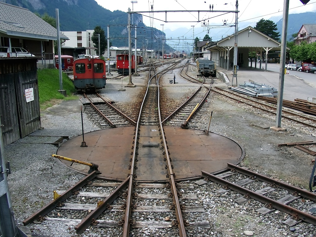 Bahnhof Meiringen 2005. Wo heute Autos stehen war vor wenigen Jahren noch eine schne kleine Drehscheibe mit dazugehrenden Abstellgleisen zu sehen. Statt den zwei Schotterwagen stehen heute zwei gedeckte Gterwagen am Gterschuppen. (23.07.2005)