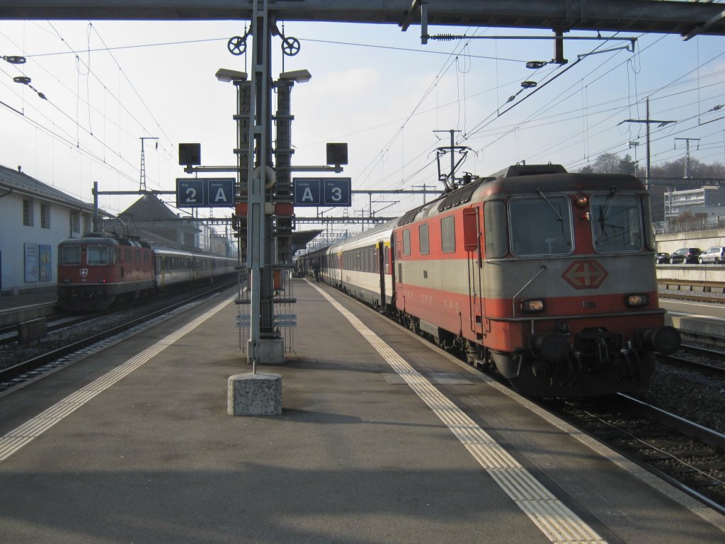 Bahnhof Morges: Links RE 2618 mit der Re 4/4 II 11125; rechts IR 1725 mit der Swiss Express Re 4/4 II 11109 (anstelle einer Re 460), 18.01.2012.