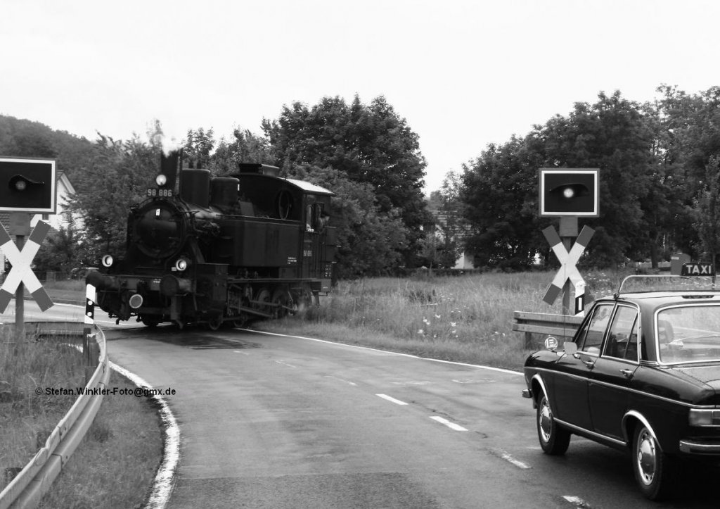 Begegnung am B in Heustreu, genau  wie anno 1971 . Die 98er rollert Lz in Richtung Mellrichstadt, am Blinklicht wartet ein Taxi. Aufgenommen am 7.7.2012 auf dem Rhnbhnle, das einen Sonderzug aus Ilmenau erwartete und deshalb die Lok solo zur Hauptbahn schickte um den Zug abzuholen....