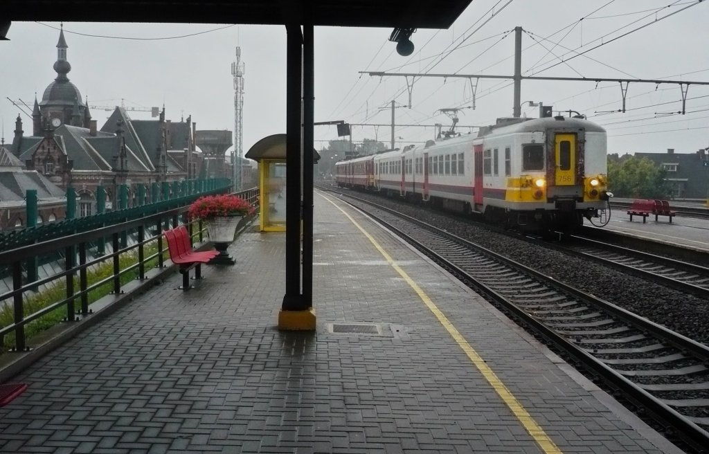 Bei herrlichem Schietwetter entstand am 16.08.2010 diese Aufnahme im ostflmischen Oudenaarde. Auf der linken Seite, befand sich frher das Bahnhofsgebude. Der heutige befindet sich genau unter mir. Bei dem sichtbar, lteren Gebude ist wohl aktuell die Zeit ein wenig stehen geblieben und doch hat das Bahnpersonal nach meinem Wissen dort noch Zutritt?!
Geplant ist, eine Kindertagessttte dort zu errichten, was in Belgien einmalig ist. Auch berhaupt sollte es eine solche Initiative weltweit nur einmal geben, nmlich in dem  Land der Bahn : CH!^^ Audenarde (Alte Erde) macht wohl den ersten Schritt fr ihr Land - es sollten aber weitere folgen, unter anderem in Antwerpen, Brssel und Charleroi.
Ein weiterer Partner dieses Projektes ist die NMBS/SNCB, die Rumlichkeiten unterliegen ja nicht zuletzt der Staatsbahn, sodass ihr, Anteile automatisch gesichert sind.
Doch noch ist´s nicht so weit und so begeben wir uns wieder in die Realitt. Stndlich verkehrt ein solcher L/R ins benachbarte Zottegem
(Fahrtrichtung Brssel).
