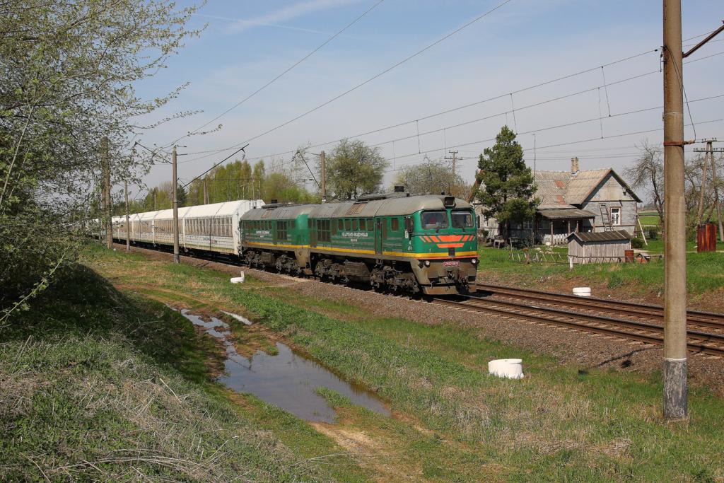 Bei der kleinen Ortschaft Gudiene in Lettland
ist am 29.4.2012 ein russischer Zug mit 2M62 0676 bespannt  
aus der Enklave Kaliningrad kommend in Richtung Vilnius unterwegs.
Der Zug besteht aus vergitterten,verschlossenen Autotransportwagen, 
in denen offensichtlich Transitgut zwischen Knigsberg und Russland
transportiert wird.