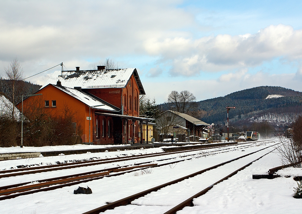 Blick auf den Bahnhof Herdorf am 09.02.2013. 
Vorne das ehem. Empfangsgebude, rechts davon der ehem. Gterschuppen und ganz hinten im Bild rechts das Stellwerk Herdorf Ost (Ho). 
Ein Stadler GTW 2/6 der Hellertalbahn kommt von Neunkirchen und fhrt gerade in den Bahnhof ein. 
Den GTW wollte ich hier eigentlich vor dem Bahnhof ablichten, aber aufgrund der nchtlichen neuen Farbgebung (Schmierereien) musste ich darauf verzichten
