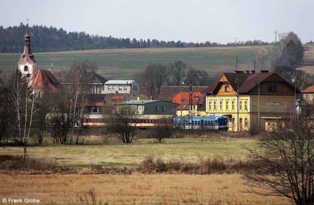 Blick auf den Ort und Bahnhof Blejov, in dem gerade ČD 842 024-2 mit zwei Wagen als Os 7413 Domalice - Plzeň eingefahren ist, ČD KBS 180 Furth im Wald – Domalice – Plzeň, fotografiert am 27.03.2012