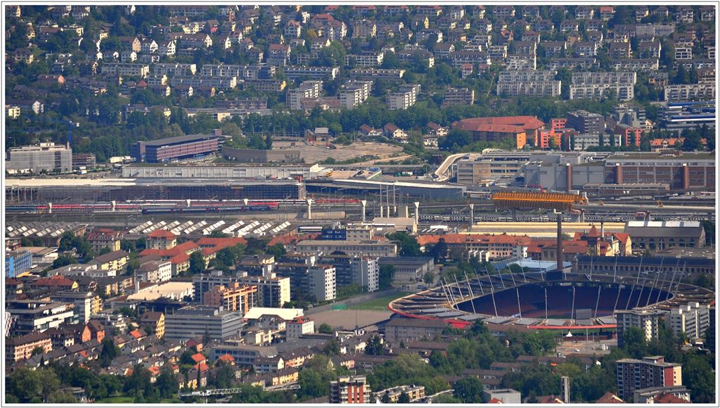 Blick vom Aussichtsturm auf dem Uetliberg Richtung Zrich Altstetten. Hinter dem Letzigrund-Stadion ist das gelbe Vorschubgerst zum Bau der neuen Letzigrabenbrcke und die einzelnen Pfeiler zu erkennen. Die Letzigrabenbrcke ist einspurig und wird die lngste Brcke der Schweiz mit 1156m. Sie verbindet Zrich Altstetten mit dem Kohledreieck, das ber eine weitere Brcke und eine Rampe mit dem neuen unterirdischen Bahnhof Lwenstrasse verbunden ist. Die neuen Brcken dienen dem Fernverkehr in Richtung Ost-West. (27.05.2013)