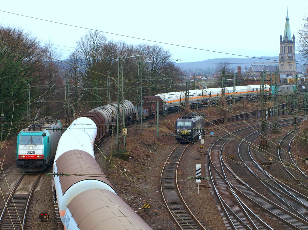 Blick durch ein Gewirr von Masten und Leitungen von der Brcke Turmstrasse in Aachen am 05.02.2010. Auf der Rampe zum Gemmenicher Tunnel begegnen sich die talwrts fahrende Cobra 186 221 und 186 198 die einen gemischten Gterzug nach Belgien zieht. Abgestellt sieht man 185 563-4 von der Rail4Chem, die mit Grafitti vollgeschmierert ist. Im Hintergrund der Turm von der Jakobskirche.