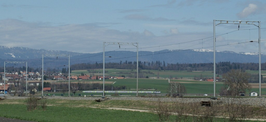 BLS Re 4/4 II mit RE 3055 Richtung Bern bei der Fahrt durchs  Grosse Moos  am 2. April 2010.
Im Vordergrund die Strecke der TPF (ex GFM) von Murten nach Ins.