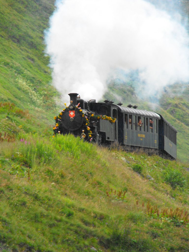 Blumengeschmueckter Sonderzug am Eroeffnungstag der Gesamtstrecke, bei der Einfahrt in die Station Furka. 12. August 2010
