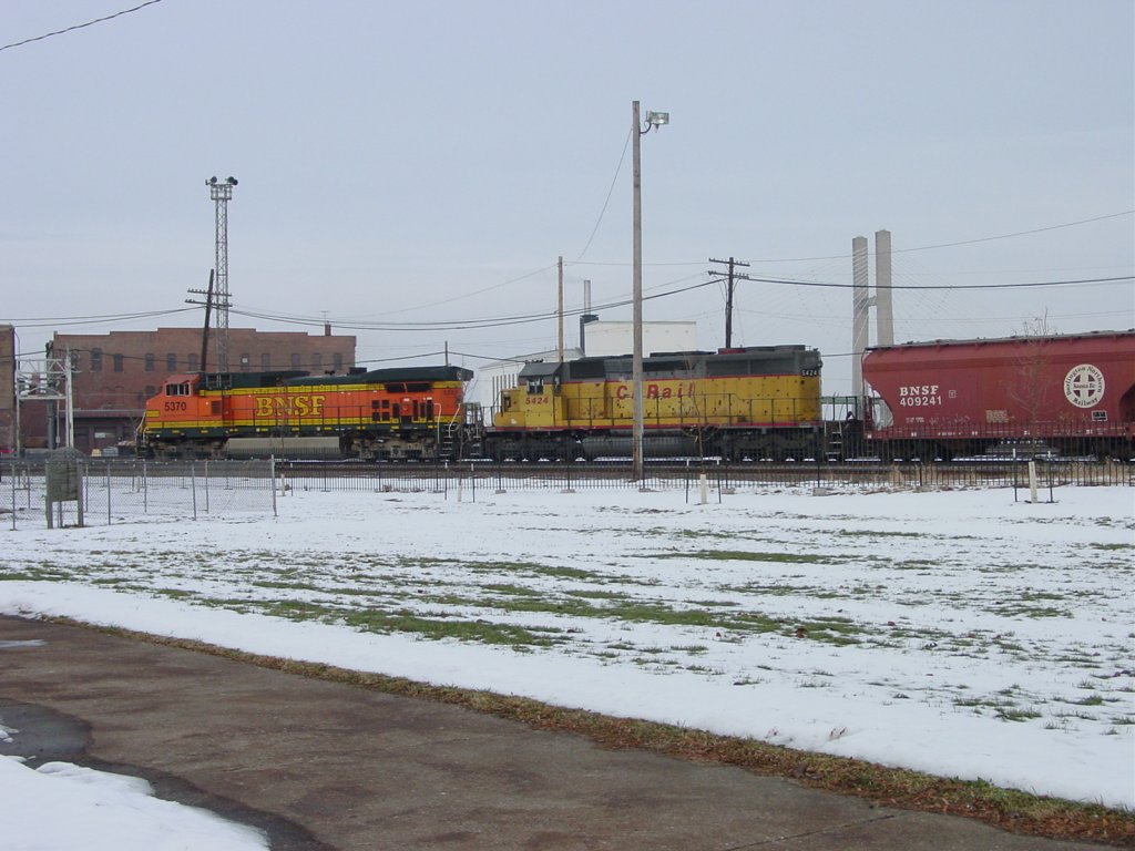 BNSF 5370 & Canadian Pacific 5424 round the curve from the freight yard onto Market Street in Burlington, Iowa. The CP unit is in the original paint scheme of the Union Pacific, just relettered and renumbered. The auto bridge towers are visible in the background. Dec. 2005