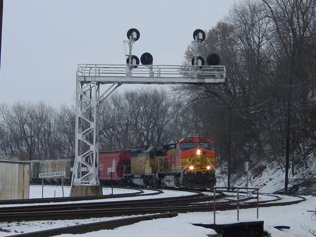 BNSF 5370 and CP Rail 5424 pull a mixed freight around the curve from across the Mississippi River in Burlington, Iowa on a cold day in December 2005. Mile Marker 205 is distance from Chicago, Illinois.