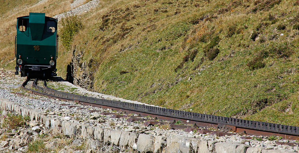 BRB-Lok16 mit nur als Schatten sichtbaren Wagen auf Talfahrt bei Strecken-km 6.5. Der Zug wird gleich den Wanderweg-Niveaubergang in der Morgenweid berqueren. Aufnahme vom 01. Okt. 2011, 14:42