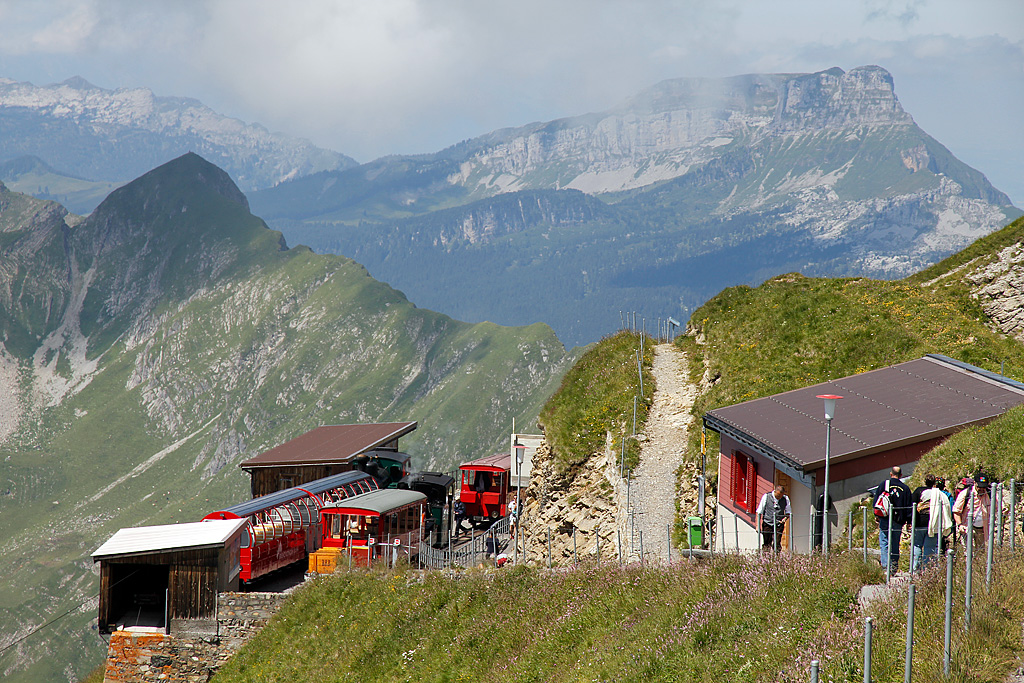 BRB-Rollmaterial aus 3 Generationen kurz nach Ankunft in Rothorn Kulm. Dahinter wimmelt es nur so von steilen Gipfeln und Bergflanken. Aufnahme vom 16. Juli 2011, 12:16 