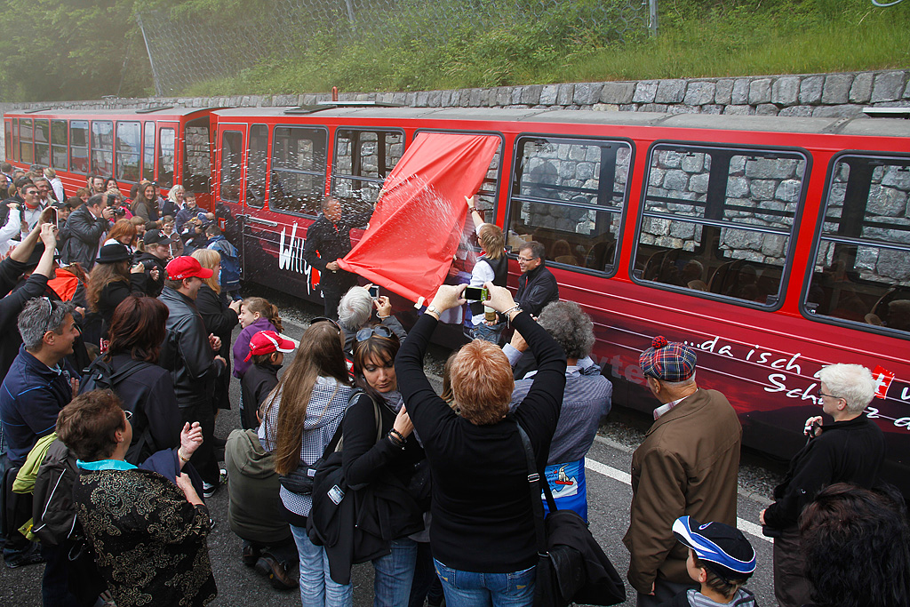 BRB-Wagentaufe des R+J-B15  Willy Tell . Es handelt sich um eine Schweizer Mundart-Rockgruppe, deren Logos, Fotos sowie weitere Angaben neu auf dem frisch revidierten Wagen prangen. Der baugleiche Wagen B14 links im Bild wurde ebenfalls innerhalb etwa 1.5 Monaten einer R1 unterzogen. BRB-Direktor Simon Koller begiesst das Ereignis tchtig mit Sekt, whrend Willy Tell und Stv.-Direktor Daniel Schlosser den Wagen enthllen. ffentlicher Anlass, Talstation Brienz, 02. Juni 2011, 13:47