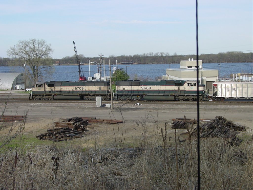 Burlington Northern 9709 & 9689 pulling empty coal drag on mainline through rail yard in Burlington, Iowa. Mississippi River in background.