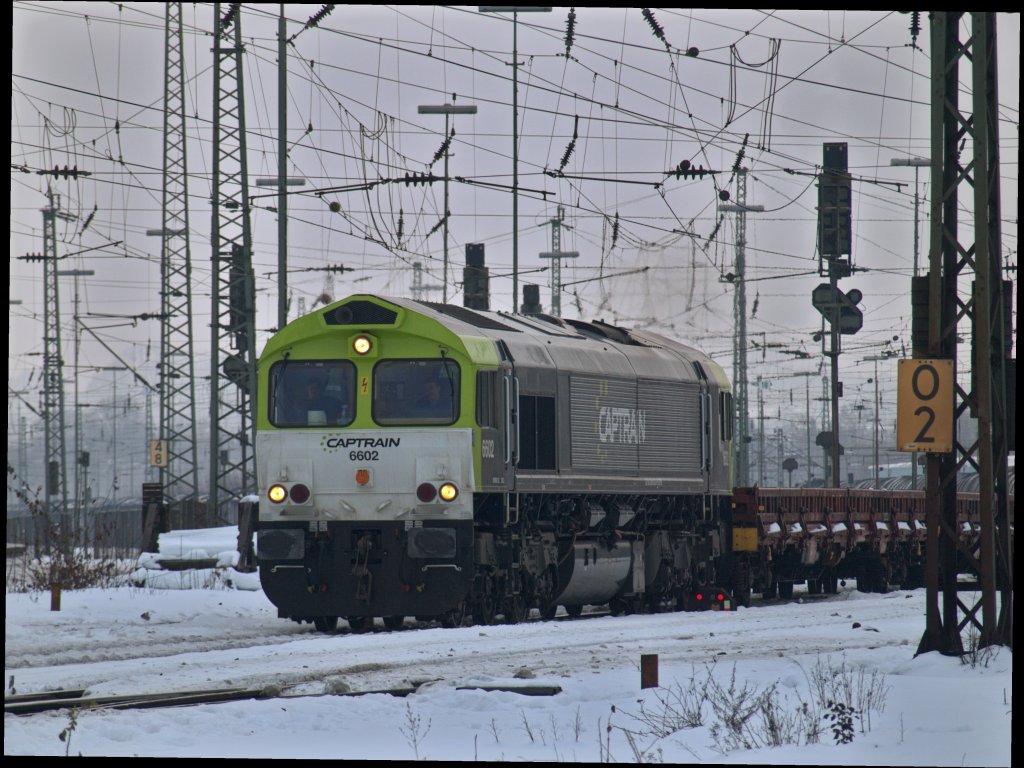 Captrain 6602 mit 4achser Flachwagen ohne Rungen am Haken fhrt am 29.12.2010 aus dem tiefverschneiten Aachen West ber die Montzenroute nach Belgien.