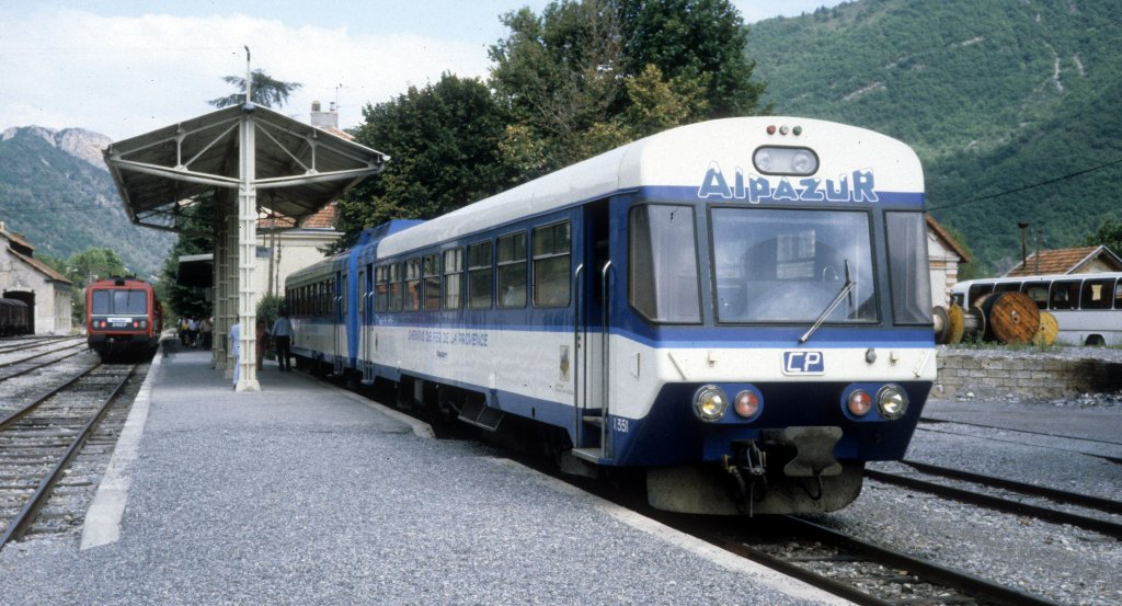 CP, Chemins de fer de Provence: Am 26. Juli 1986 hlt der Soul-Garnro-Doppeltriebwagen X351 + XR1351 (Bj 1984) am Bahnsteig im SNCF-Bahnhof Digne. - Der Zug wird kurz danach in Richtung Nice / Nizza fahren. - Im Hintergrund sieht man einen Triebzug der SNCF, der eben von Grenoble ber Saint-Auban angekommen ist. - In den Jahren 1981 bis 1989 existierte die sogenannte Alpazur, eine Zusammenarbeit zwischen der SNCF und den CP, die den Fahrgsten von Genf oder Grenoble nach Nizza eine krzere und schnellere Verbindung anbot, als wenn sie ber Marseille gefahren wren. - Seit der Stillegung der Bahnstrecke Saint-Auban - Digne durch die SNCF im Jahre 1989 gibt es diese Reisemglichkeit nicht mehr.
