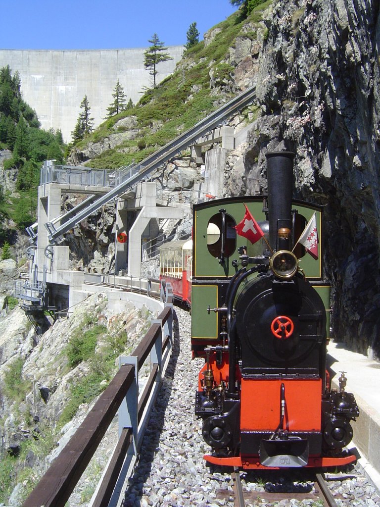Dampflok Jung Nr. 1693 (1911), Spur 60cm,  Liseli . 
Einsatz auf der Panoramabahn  Parc d'Attractions du Chatelard (VS) .
Ausnahmsweise ermglichte Aufnahme erfolgte im Bahnhof  Pied du Barrage  unter ausdrcklicher Genehmigung des Bahnpersonals und sicherheitstechnischer Begleitung derselben; im Hintergrund die Fahrbahn des Schrgaufzugs  Minifunic  und ganz hinten die Staumauer des  Lac d'Emosson , 03.07.2011
