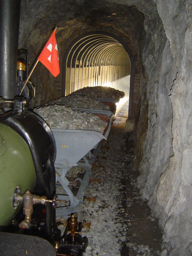 Dampflok Jung Nr. 1693 (1911), Spur 60cm,  Liseli . Einsatz auf der Panoramabahn  Parc d'Attractions du Chatelard (VS) . Bauzug mit schotterbeladenen Kipploren innerhalb Tunnel Nr. 4, Fahrt rckwrts in Richtung  Pied du Barrage . Dieses einmalige Foto entstand durch das Fhrerstandsfenster heraus (das Betreten der Tunnels ist selbstverstndlich zu gefhrlich und deshalb streng verboten). Hinten ist der Galerieabschnitt sichtbar; das Sonnenlicht beleuchtet die Szene zustzlich von der Seite her. 20.10.2007