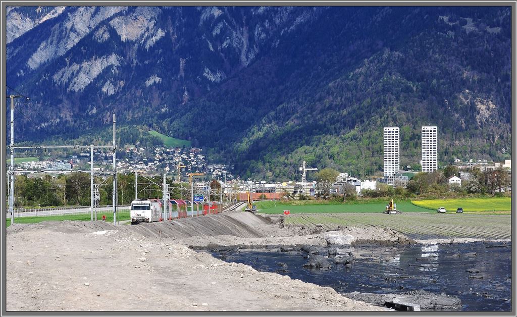 Das erste Auffangbecken beim Bahnhof Felsberg ist bereits voll. Die schwarze schiefrige Schlammmasse hat auch viel Gerll und Bume mitgebracht. Das Tiefbauamt und auch die Armee versuchen mit schwerem Gert die bedrohliche Lage zu entschrfen. Whrenddessen zieht Ge 4/4 III 643  Vals  den RE1153/GEX910 am Schlamassel vorbei Richtung St.Moritz. Rfe Pargheratobel. (27.04.2013)