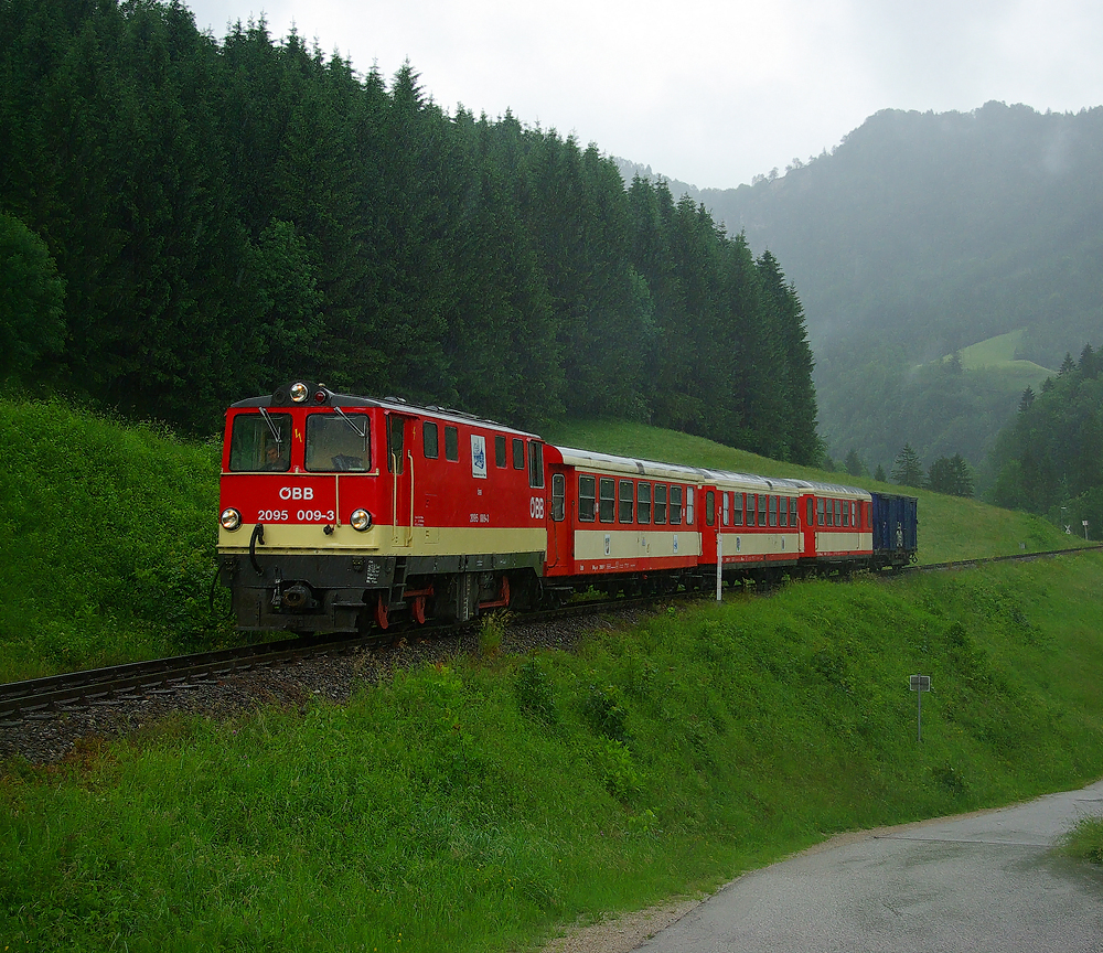 Das Jahr 2009 war das letzte Betriebsjahr der Ybbstalbahn in welchem ein durchgehender Bahnverkehr zwischen Waidhofen und Lunz am See mglich war. 
Bedingt durch starke Regenflle kam es im Frhsommer 2009 zu kleinen Vermurungen der Strecke welche die Bundebahnen als willkommenen vorgezogenen Einstellungsgrund ausntzten. 

Ebenfalls im Frhsommer 2009, nmlich am 30.05. war ich bei bescheidenem Wetter im Ybbstal unterwegs, und habe diesen Regionalzug gezogen von der 2095 009 in der Nhe von Gstadt in Fahrtrichtung Lunz am See aufgenommen. Wenige Tage spter war mit den Regionalzgen nach Lunz Sense.