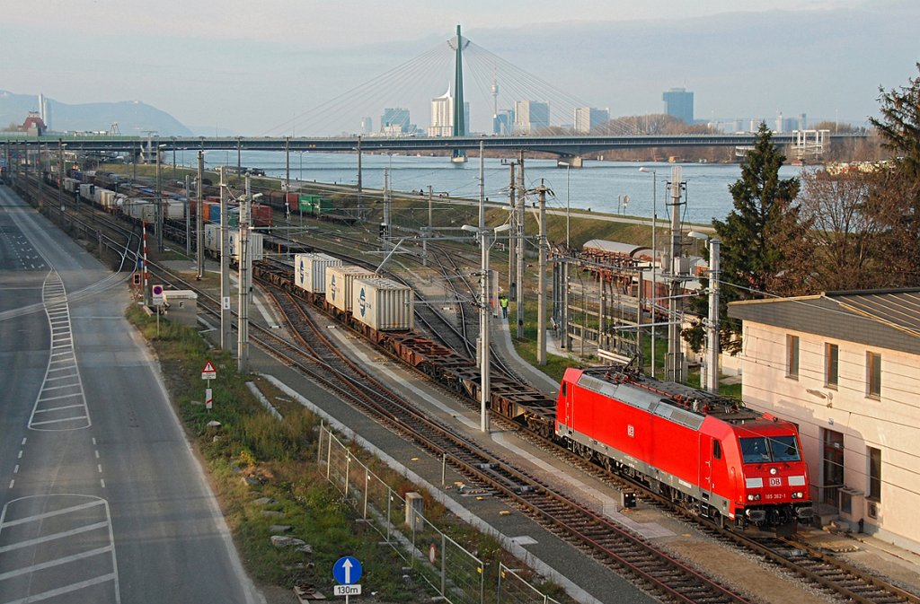 DB 185 362 mit einem Containerzug Richtung Alberner Hafen. Die Aufnahme entstand in der Nachmittagssonne am 05.12.2009. Links im HG ist der Leopoldsberg zu erkennen, rechts im HG der Donauturm und die Gebude der Wr. UNO City, davor die Brcke ber die Donau der A 23, eine der meistbefahrensten Straen in sterreich.