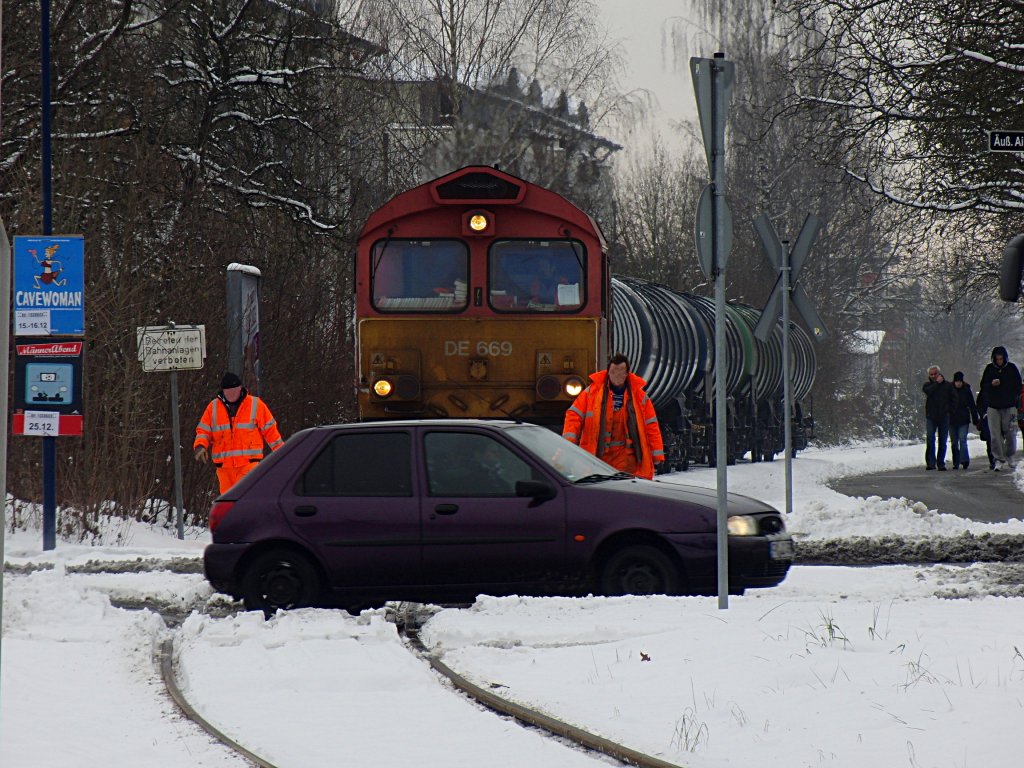 DE 669 der HGK muss mit den mit Heizl befllten Kesselwagen am 03.12.2010 an einem unbeschrankten und nicht mit Lichtzeichen ausgestatteten Bahnbergang solange mit der berfahrt warten, bis zwei Bahnmitarbeiter den bergang gesichert haben. DE 669 befindet sich auf der Fahrt von Friedrichshafen Gbf ins Industriegebiet Friedrichshafen, um einen Heizlhndler zu beliefern.