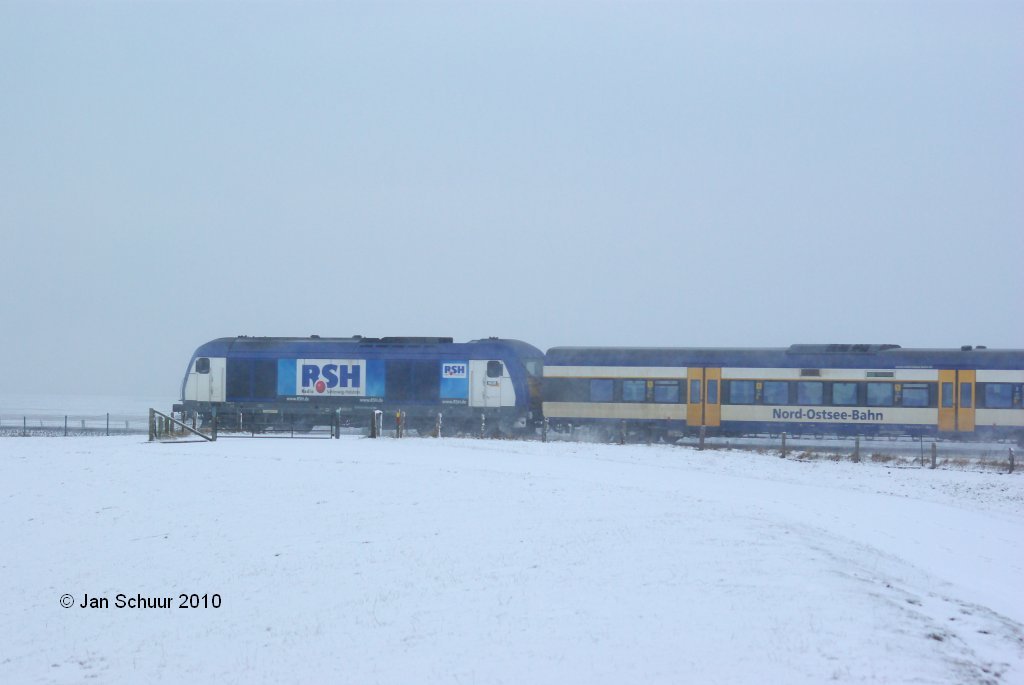 DE2000-33 der Nord-Ostsee-Bahn (NOB) genau an der Schnittstelle von Hindenburgdamm und dem Festlandschutzdeich am 02.01.2010 auf dem Weg von Sylt nach Niebll (-Hamburg).

Man beachte hier die RSH-Werbung.

 Jan Schuur 2010