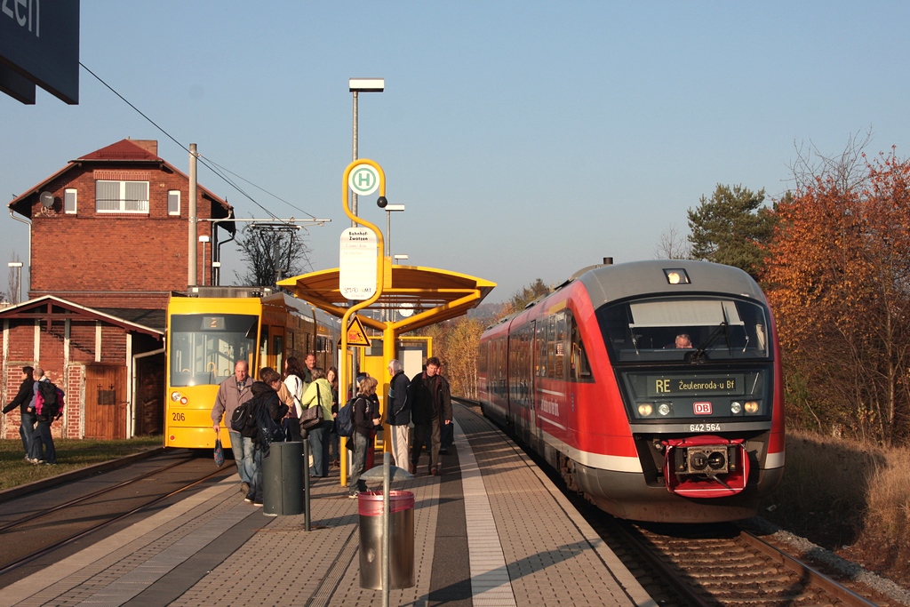 Den Hp Gera-Zwtzen hat soeben 642 564/064 als RB16475 erreicht und am  Nachbargleis  der GVB, an der Hst. Zwtzen Bahnhof, steht NGT8G 206 als Linie 2 nach Lusan/Brte bereit. Diese Stn. ist im Design der GVB gestaltet und auch die Reisenden im Vordergrund warten auf den Anschlu an die Buslinie 16.  