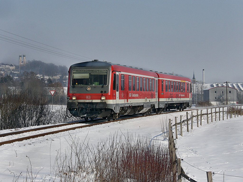 Der 628 576 als RB nach Mhldorf am 16.02.2010 bei der Ausfahrt aus Pfarrkirchen mit der Gartlbergkirche und der Stadtpfarrkirche im Hintergrund. 