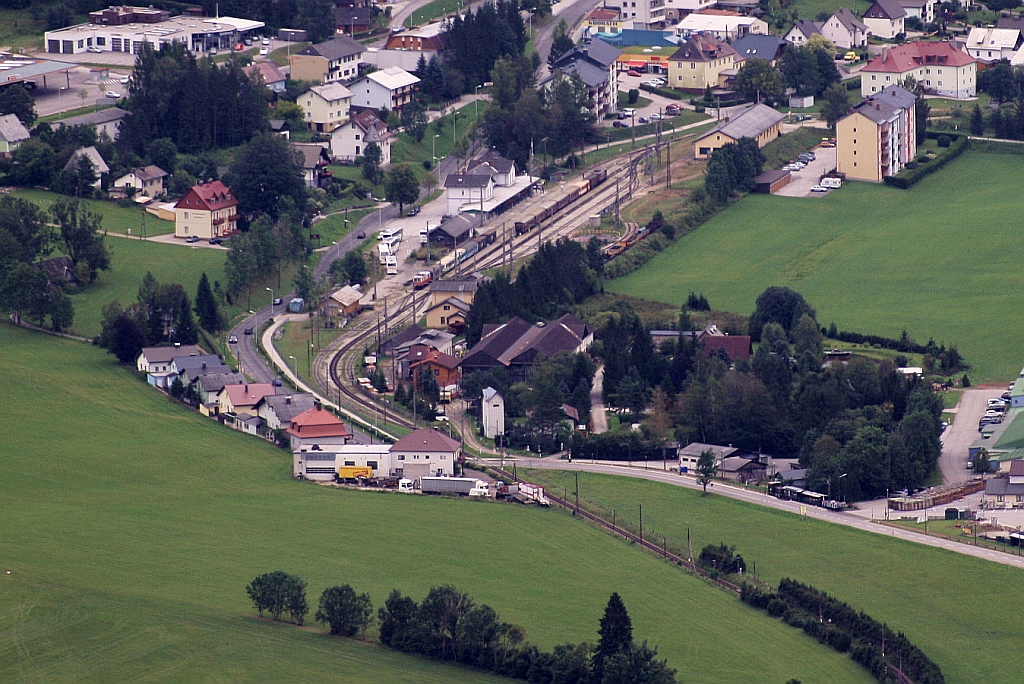 Der 850,50m hoch gelegene Bahnhof Mariazell von der 1626m hohen Gemeindealpe aus gesehen. Im Bahnhof steht in Richtung St. P�lten die 1099 002 mit dem REX6814  Dirndltaler  und in Richtung Gusswerk die 1099 007 mit dem R6811 aus G�sing, welche nun auf den REX6810  �tscherb�r  wenden wird. Weiters erkennt man einen Zug der Museumstramway Mariazell. Bild vom 25.August 2012.