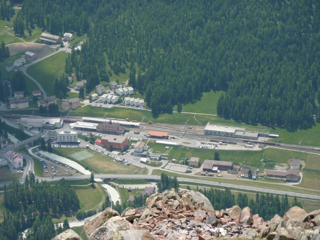 Der Bahnhof Pontresina am 4.7.2010 aus der Vogelperspektive. Rechts sieht man die Stelle, an der sich die Strecken nach Scoul-Tarasp und St. Moritz teilen. Im Bahnhof steht der abgestellte Bernina Express, der auch auf dem nachfolgendem Bild zu sehen ist und rechts sieht man zwei kurze Holzzge. Aufgenommen auf dem Hhenweg zwischen Muottas Muragl und der Alp Languard.