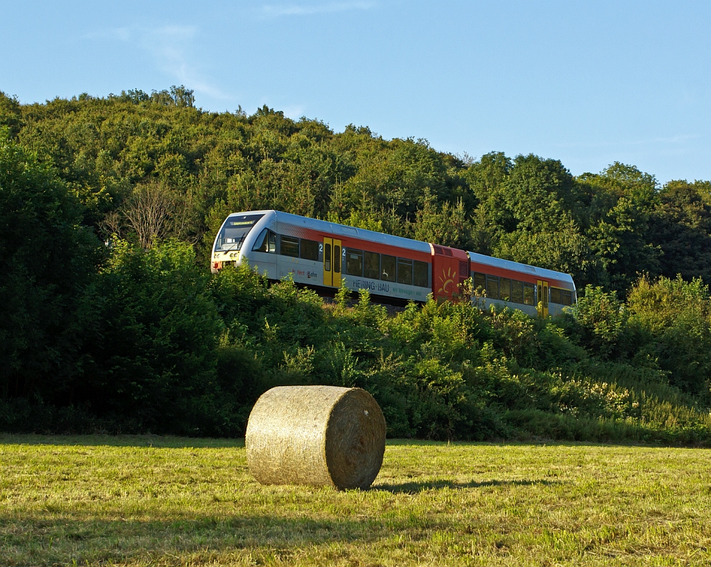 Der Bauer hat die Heuernte noch auf der Wiese und die Hellertalbahn fhrt am 27.07.2012 mit einem Stadler GTW 2/6 in Richtung Betzdorf, hier bei Herdorf-Sassenroth.