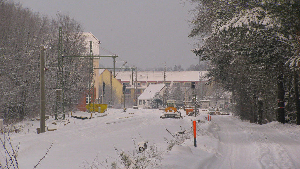 Der Blick in Richtung Bahnhof Bestensee zeigt, dass die Bauarbeiten erstmal auf Eis liegen. Die Planierraupe hat bis zu ihrem Standpunkt bereits neuen Schotter ausgebreitet, aber dann war Schluss und so steht sie nun seit 3 Wochen im Schnee und wartet auf den Frhling. Der Umbau der Strecke in Bestensee, bringt erstmalig 2-Gleise ber spannende Masten hierher. (19.12.2010)