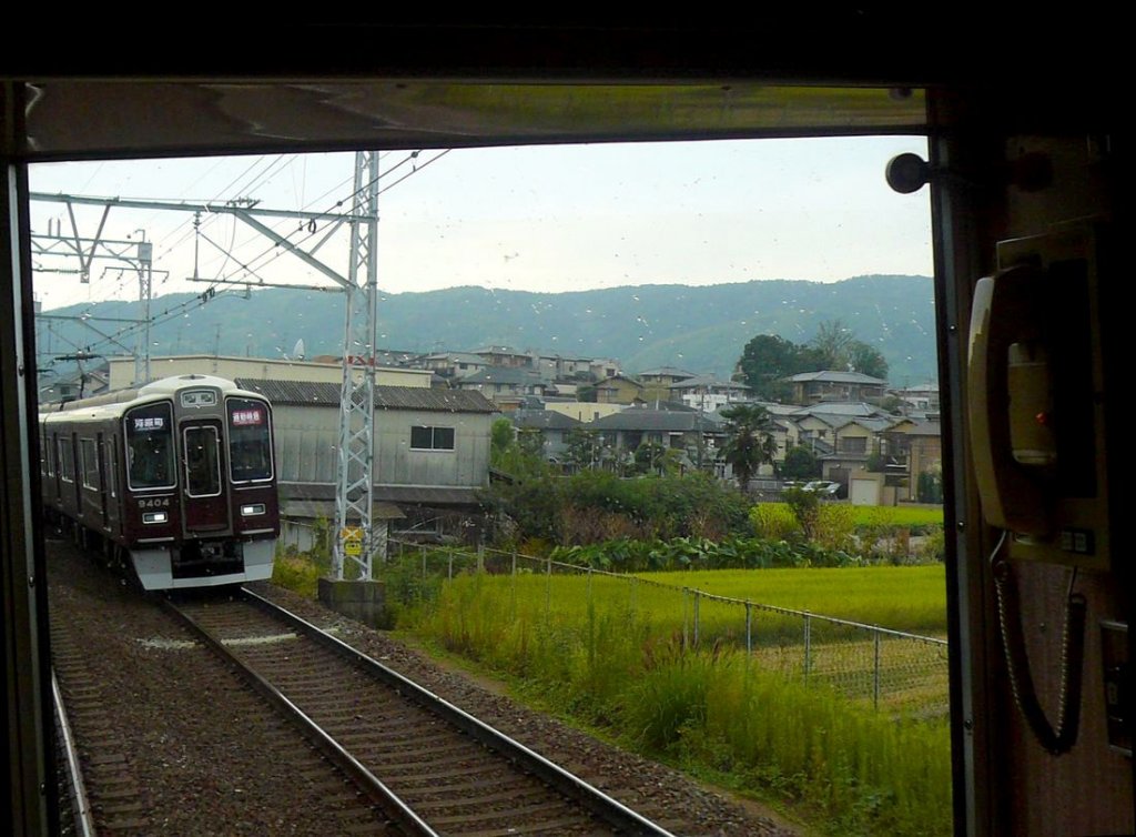 Der Hankyû-Konzern - Die Züge der 2000er Jahre: Serie 9300. An einem regnerischen Morgen begegnet Zug 9304 (Endwagen 9404) auf der Fahrt von Osaka nach Kyoto. Aufnahme durch die verglaste Führerstandrückwand, Nagaoka Tenjin (Kyoto), 28.September 2009. 