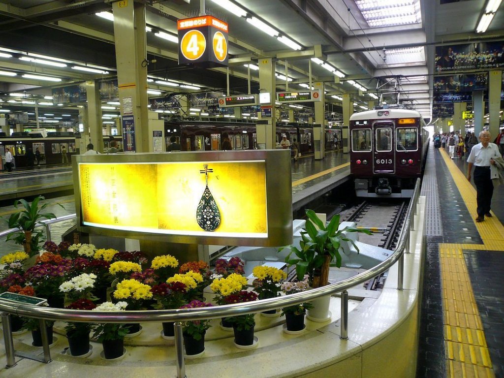 Der Hankyû-Konzern:  Tradition  ist das Markenzeichen dieser Bahn - im Hauptbahnhof Osaka-Umeda kommt Zug 6013 in ihrem einheitlich-traditionellen Anstrich zu stehen vor einer Leuchtreklame für die alten kaiserlichen Kunstschätze, repräsentiert durch eine Laute aus dem 8.Jahrhundert. 28.September 2009. 