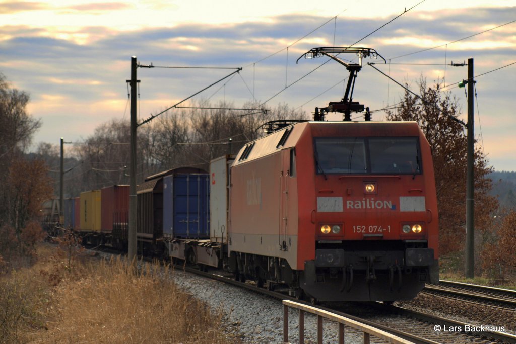 Der Himmel glht. 152 074-1  entflieht  am 12.02.11 mit einem langen Containerzug Hafeneinwrts diesem  Inferno . Aufgenommen in Hamburg-Moorburg.